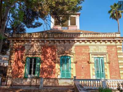 Queste, delimitate da lesene bugnate angolari, presentano tre aperture con persiane verdi...